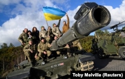 Українські військовослужбовці позують на танку Challenger 2 на військовій базі Bovington Camp на південному заході Великої Британії, де проходять навчання, 22 лютого 2023 року